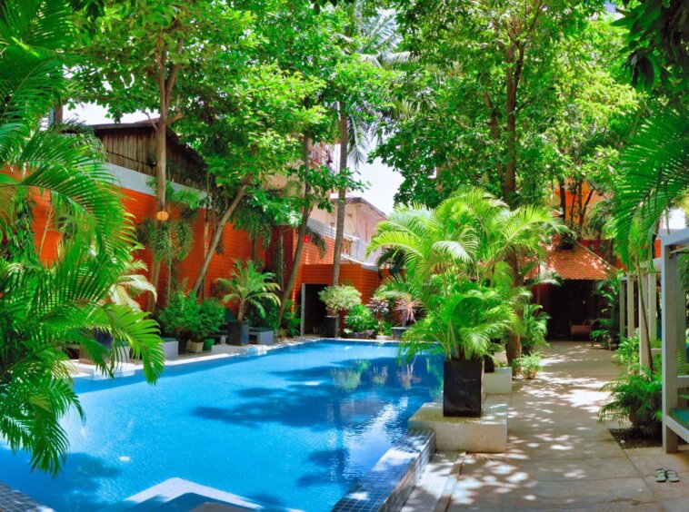 Photo by allPhoto Bangkok a large swimming pool surrounded by lush green trees